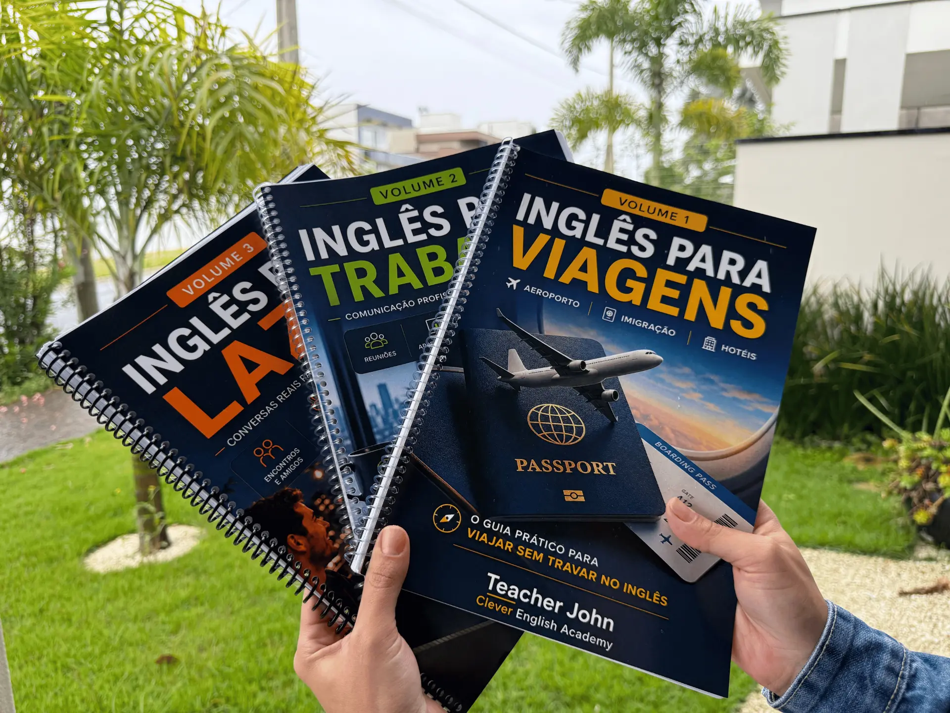 Os três volumes impressos sendo segurados nas mãos